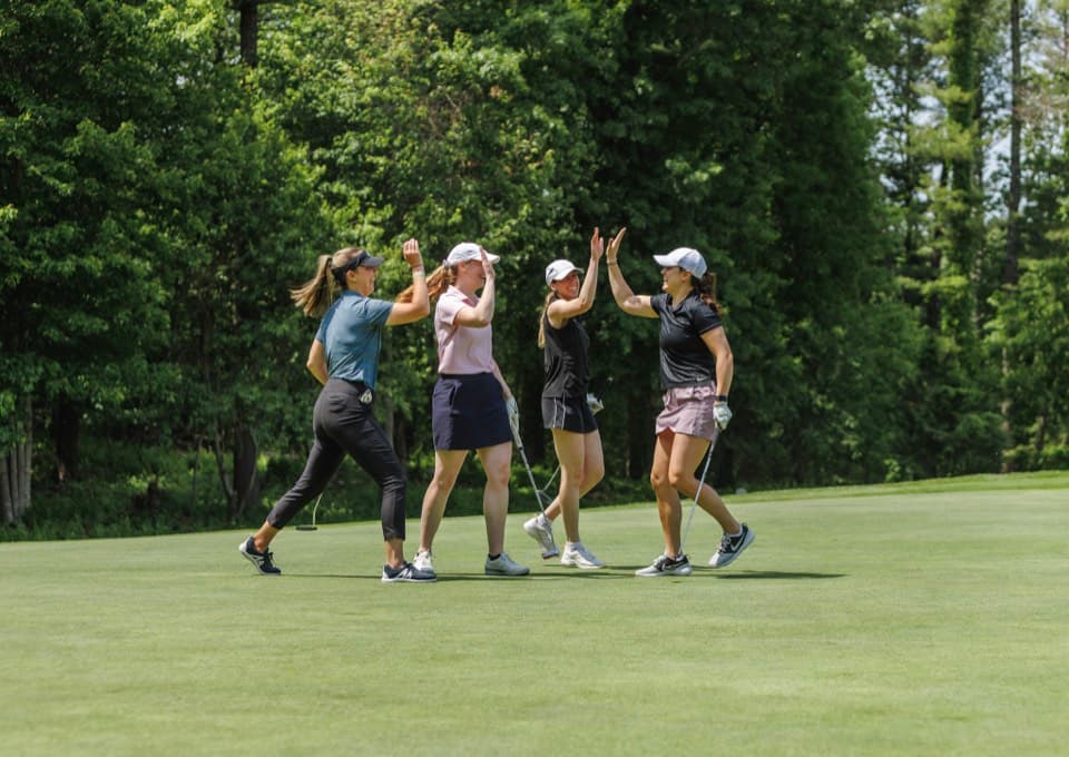 Women high-fiving on the course